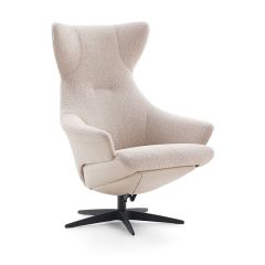 schuinaanzicht beige relaxfauteuil Borgognona van Baenks. De fauteuil heeft een lange rugleuning met op de uiteinden een soort kattenoren. De vijfteens voet is gemaakt van zwart metaal.