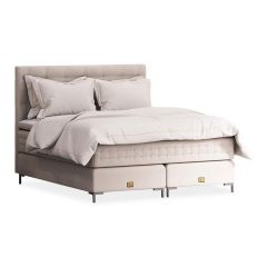 Luxe Mattsons Soulful bed met een elegant ontwerp in beige, compleet opgemaakt met hoogwaardige beddengoed en gouden details op de bedpoten.