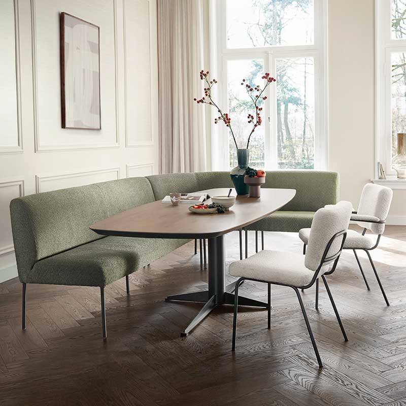 Eettafel met groene eetkamerbank, beige eetkamerstoelen en decoratieve vaas