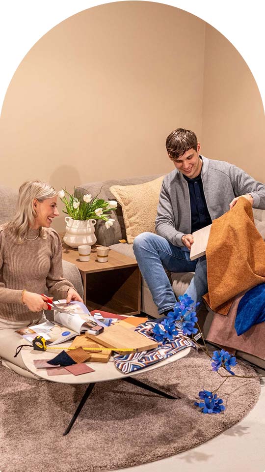 Een jonge man en vrouw zoeken samen klueren en stoffen uit voor hun interieur