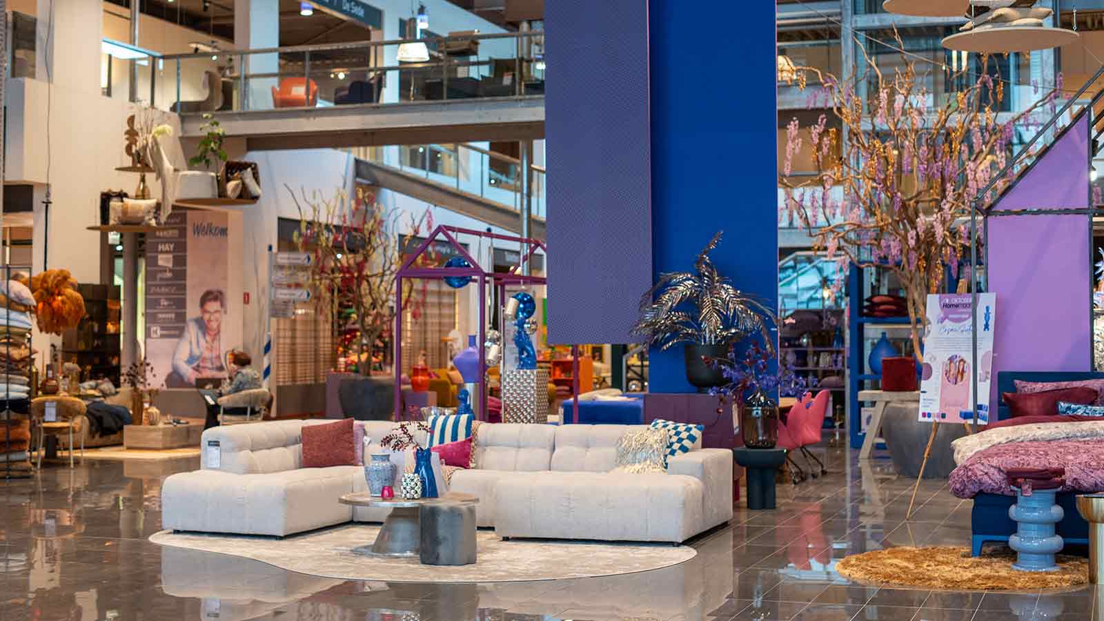 Entree van Home Center met kleurrijke decoraties, moderne meubels en opvallende blauw-paarse accenten